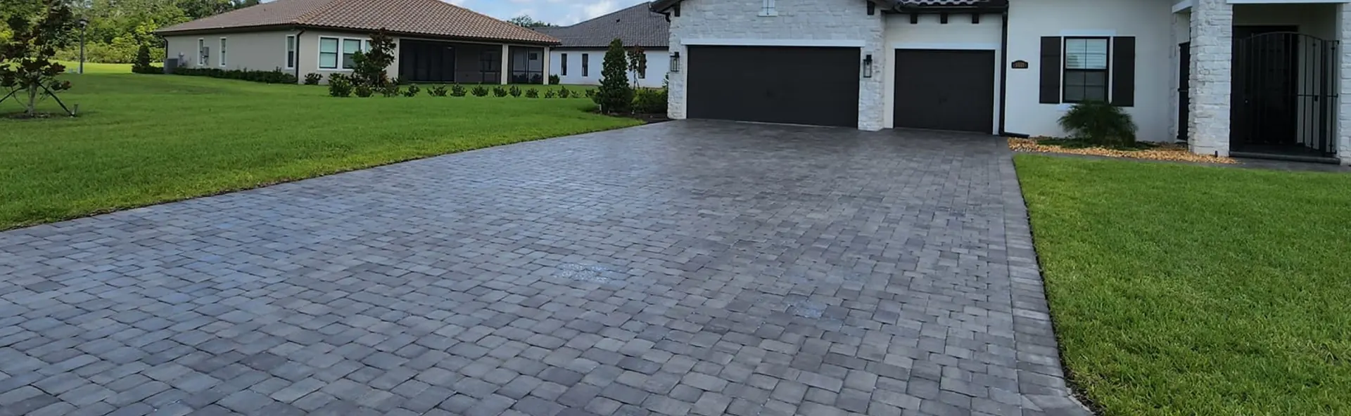 Gray paver driveway leading to a two-car garage