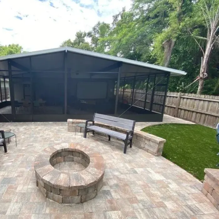 Paver patio and fire pit next to a screened pool enclosure
